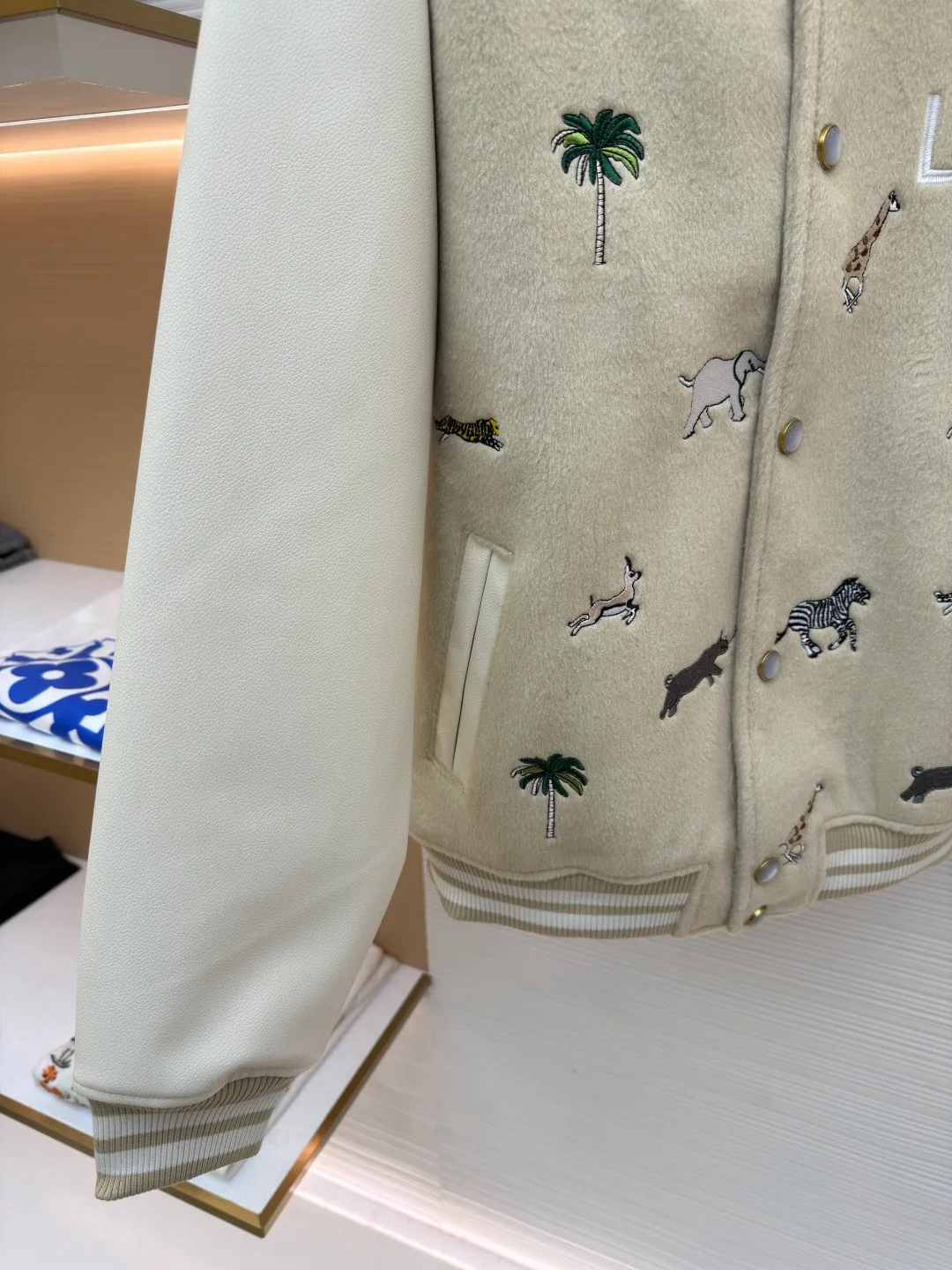 LOUIS VUITTON animal embroidered baseball uniform ●Original version: 48000 purchased and developed ●Item number: 1682284-B90 ●Fabric: cotton fabric ●Technology: embroidery production ●Color: apricot ●Version: fitted version ●Weight: about 1070 grams ●Size: 46-48-50-52 ●Description: The main body of this Louis Vuitton embroidered baseball jacket is made of high-quality wool blended fabric, which is crisp and soft. The sleeves are made of eco-friendly artificial leather with a matte texture, which contrasts with the body in terms of material and touch. The animal, palm tree and other patterns on the body of the clothing are all completed by hand-stitched embroidery technology, using multi-color embroidery threads to embroider in layers. The patterns are three-dimensional and vivid, and the stitching in the details is fine and even. The letter logo uses flat embroidery technology, and the font outline is clear and regular. The ribbed collar, cuffs and hem of the jacket are made of high-elastic knitted fabric, which will not loosen easily after being worn for a long time. The metal snaps on the placket are custom-made hardware with a thick texture and anti-oxidation. The overall tailoring is a loose oversize version, and the splicing uses hemming stitching technology, and the lines are smooth and smooth. Every craft detail is in line with the brand's luxury product production standards, creating a ready-to-wear garment that has both a sense of design and practical wearability. The overall wiring is straight and delicate, the fabric is comfortable and soft, and the color is consistent without color difference. It can be matched with the same style to create a fashionable look and control various occasions. Customized accessories, complete with three standards, same style for men and women!